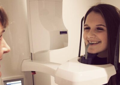 a dental assistant speaking with a smiling teenage patient