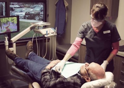 dental assistant speaking with senior gentleman patient